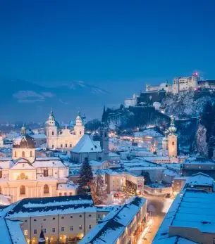 Salzburg's illuminated baroque architecture and hilltop fortress create a magical winter evening cityscape