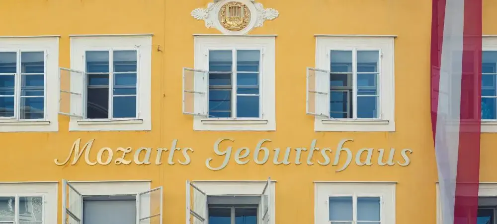 Mozart's birthplace in Salzburg featuring yellow baroque facade with white shuttered windows and Austrian flag