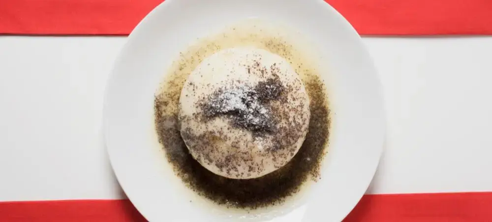 Traditional Austrian Salzburger Nockerl soufflé dessert dusted with powdered sugar on white plate