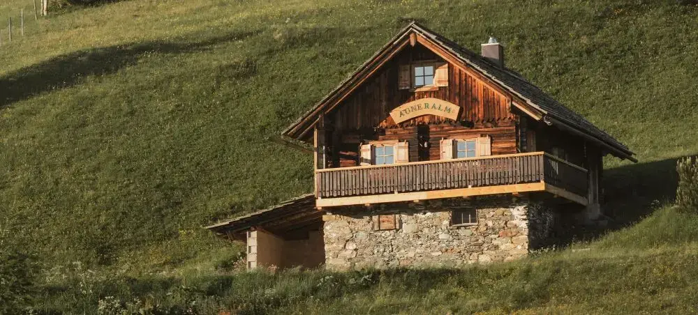 Traditional Austrian alpine chalet with wooden balcony nestled in green mountain meadows near Salzburg