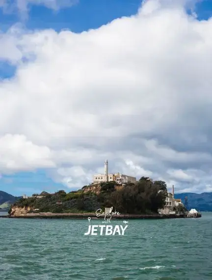 Alcatraz Island prison complex surrounded by San Francisco Bay waters under dramatic cloudy skies
