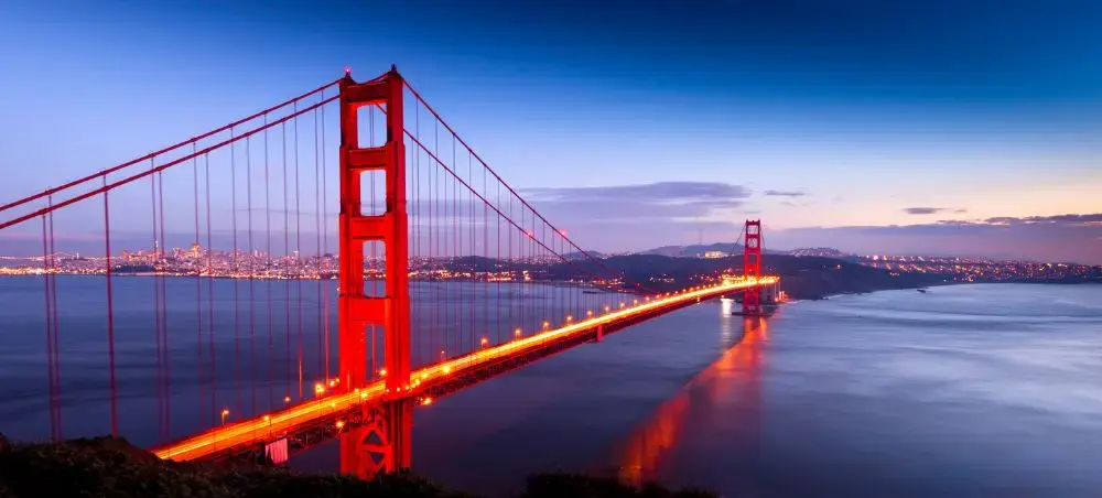 Golden Gate Bridge illuminated at twilight with San Francisco skyline, showcasing luxury travel destination