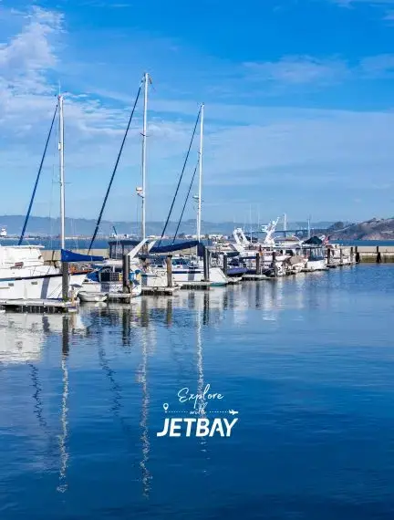 Luxury marina with sailboats and yachts reflecting in calm San Francisco Bay waters under blue skies