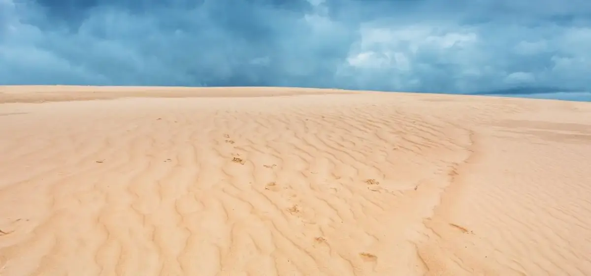 Expansive golden sand dunes under dramatic blue sky showcasing Bolivia's diverse landscapes for luxury travel