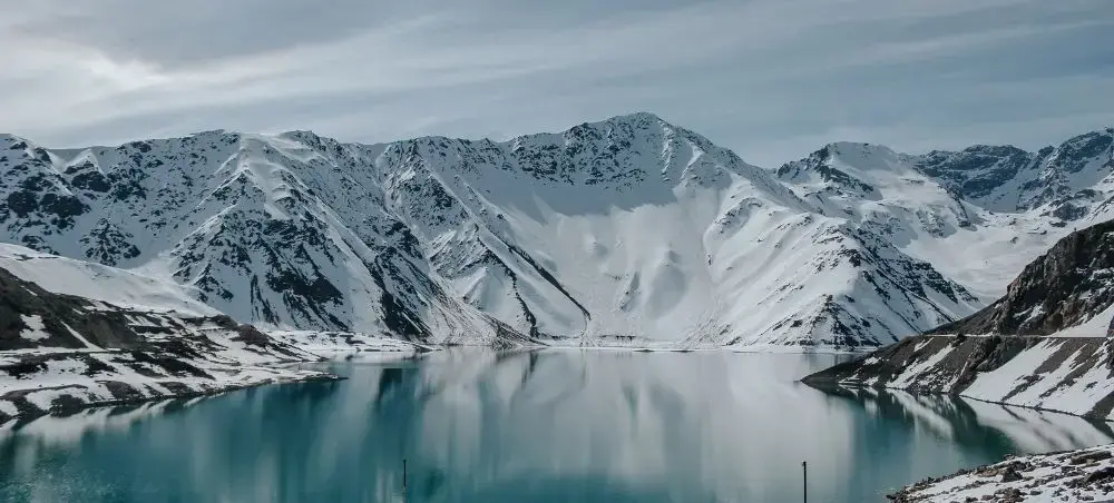 Snow-capped Andes mountains reflected in pristine alpine lake near Santiago, Chile's premier destination