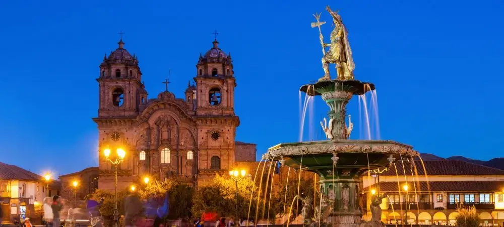 Historic colonial cathedral and ornate fountain illuminated at twilight in Santiago's main plaza