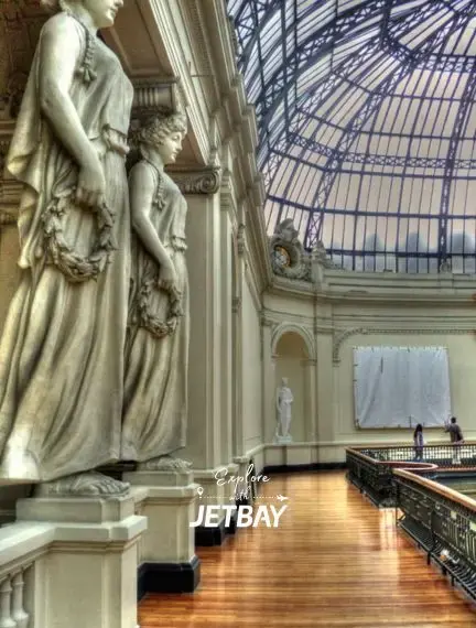Elegant neoclassical statues and glass dome ceiling inside Santiago's historic Palacio de La Moneda cultural center