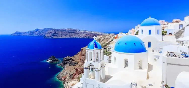 Iconic blue-domed churches overlooking azure Aegean Sea in Santorini, Greece's premier luxury destination