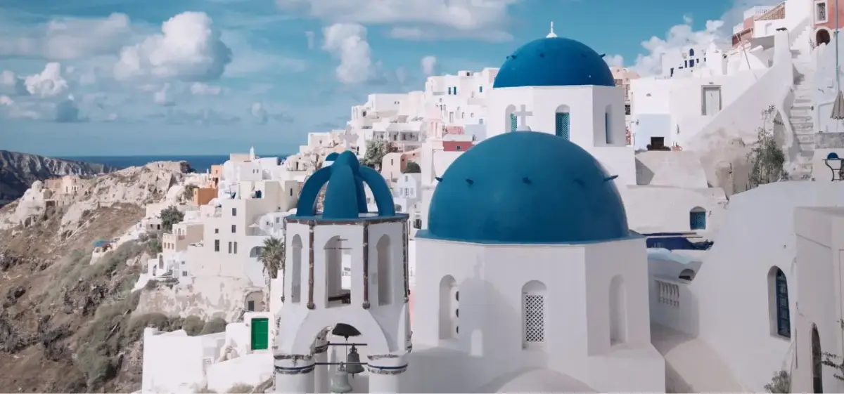 Iconic blue-domed churches and whitewashed buildings cascading down clifftops in Santorini, Greece