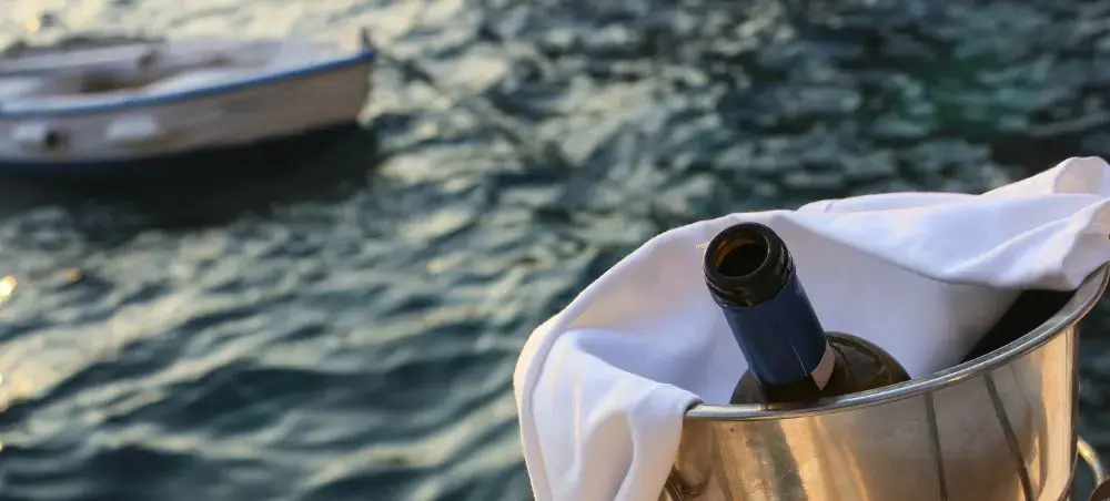 Champagne chilling in ice bucket aboard luxury yacht with Santorini waters and boat in background
