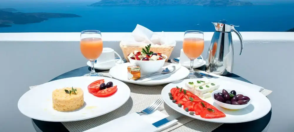Elegant breakfast spread with Greek delicacies overlooking Santorini's azure caldera waters