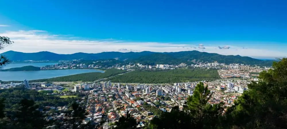 Panoramic aerial view of São Paulo's sprawling urban landscape with mountains and blue skies