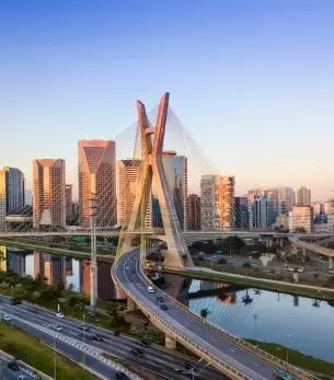 São Paulo skyline at sunset featuring iconic cable-stayed bridge over Pinheiros River in Brazil