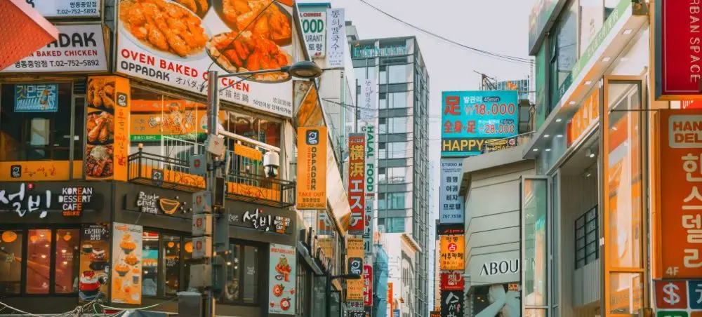 Bustling Seoul street lined with colorful Korean restaurant signs and modern buildings in South Korea