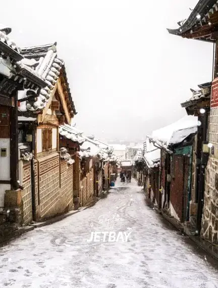 Snow-covered traditional Korean hanok houses line historic Bukchon village street in Seoul winter