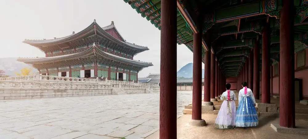 Two women in traditional Korean hanbok dresses walking through Gyeongbokgung Palace courtyard in Seoul