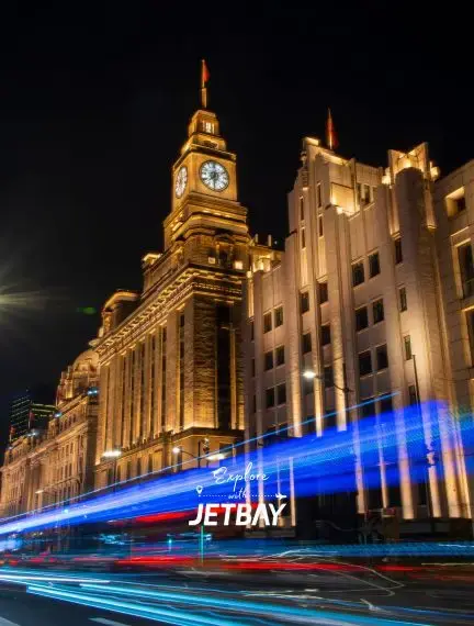 Shanghai's iconic Bund waterfront illuminated at night with historic colonial architecture and Jetbay branding