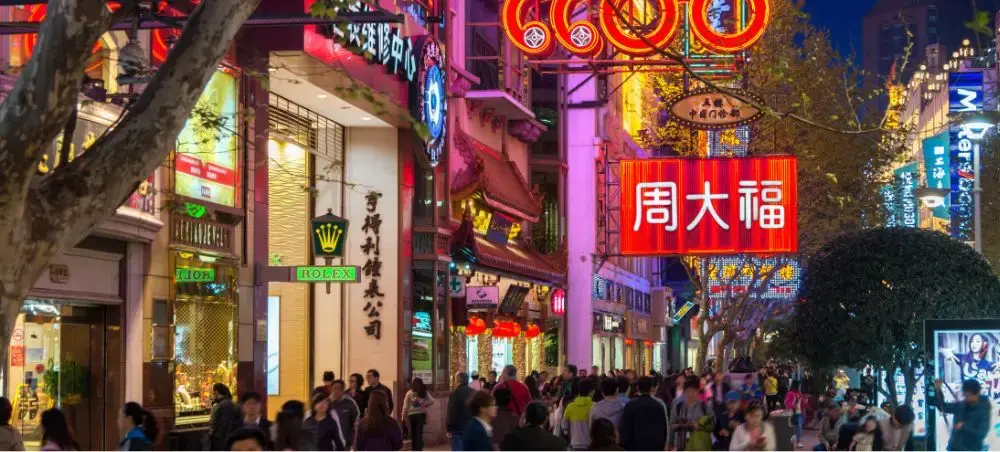 Bustling Shanghai shopping street at night with neon signs and crowds exploring luxury retail destinations