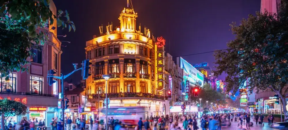 Bustling Shanghai pedestrian street at night with illuminated historic buildings and vibrant neon signs