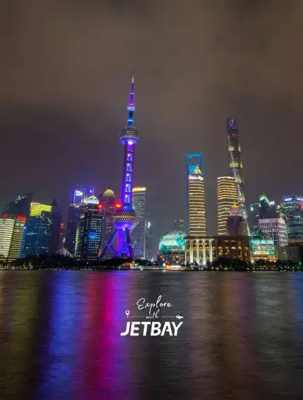 Shanghai's illuminated Pudong skyline featuring Oriental Pearl Tower and modern skyscrapers reflected in Huangpu River at night