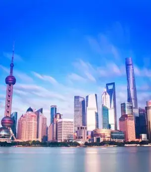 Shanghai skyline featuring Oriental Pearl Tower and modern skyscrapers reflecting in Huangpu River at dusk