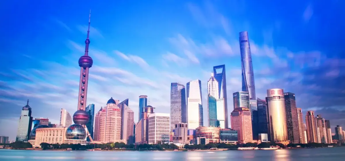 Shanghai skyline featuring Oriental Pearl Tower and modern skyscrapers reflected in Huangpu River at dusk