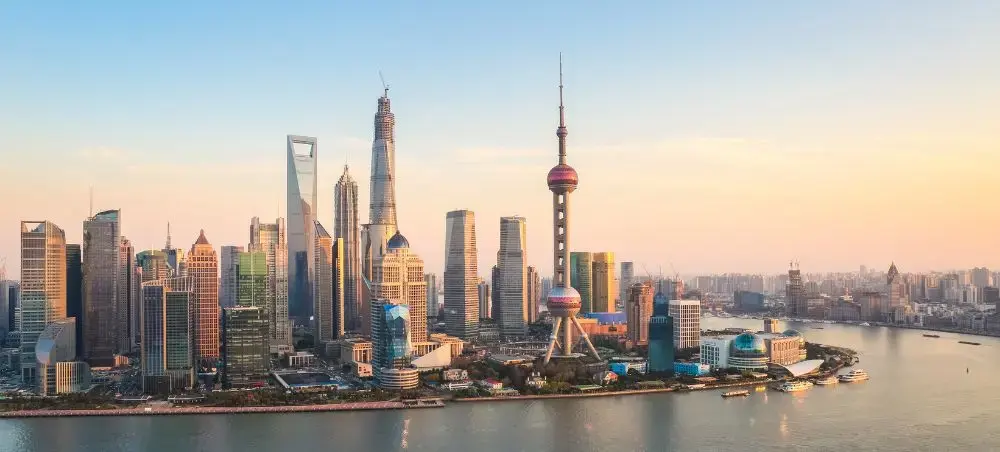 Shanghai's iconic skyline featuring Oriental Pearl Tower and modern skyscrapers along the Huangpu River at sunset