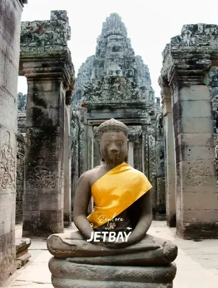 Ancient Buddha statue draped in saffron robes at Bayon Temple in Angkor Thom, Siem Reap Cambodia