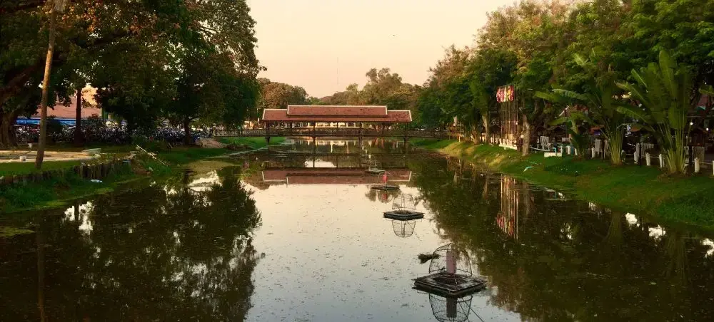 Serene canal with traditional boats reflecting golden sunset light in historic Siem Reap, Cambodia