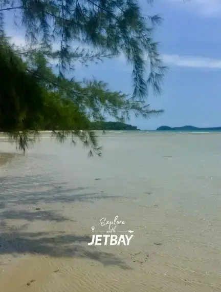 Pristine white sand beach with crystal clear waters and tropical trees in Sihanoukville, Cambodia