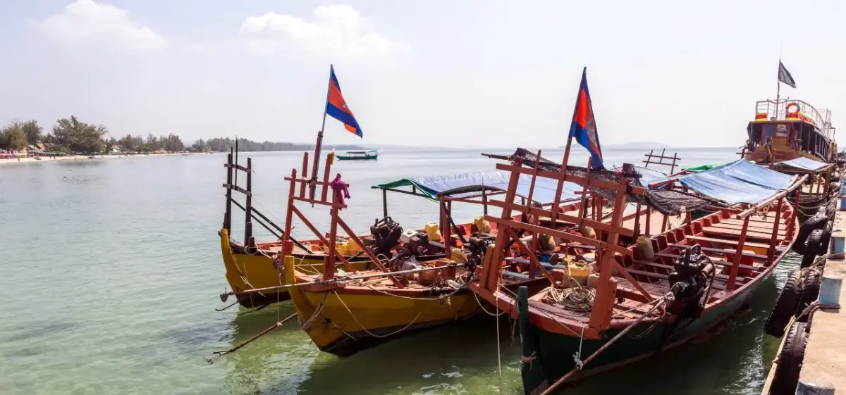 Traditional Cambodian fishing boats with colorful flags docked at Sihanoukville harbor waterfront