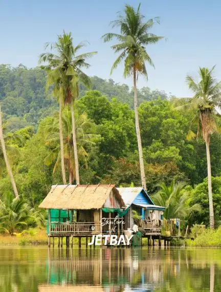 Traditional stilt houses reflect in calm waters surrounded by tropical palms in Sihanoukville Cambodia