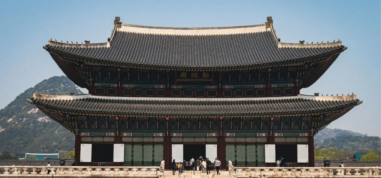 Traditional Korean palace architecture with ornate curved rooflines and mountains showcasing Seoul's cultural heritage