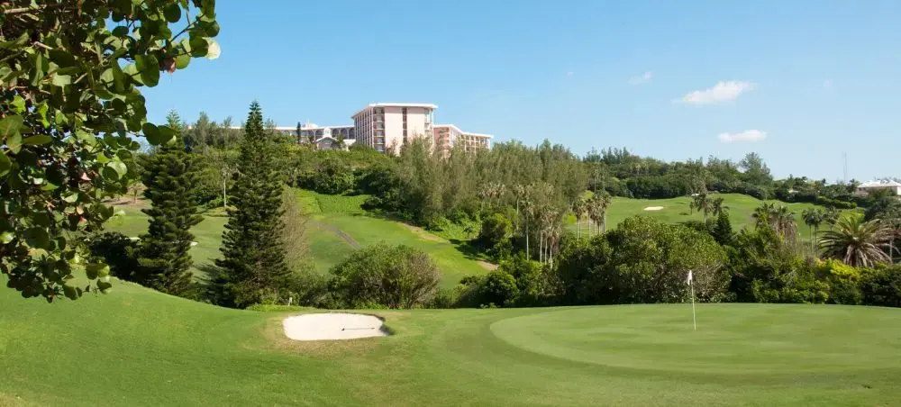 Pristine golf course with sand bunker and flag in Southampton, Bermuda surrounded by lush tropical vegetation
