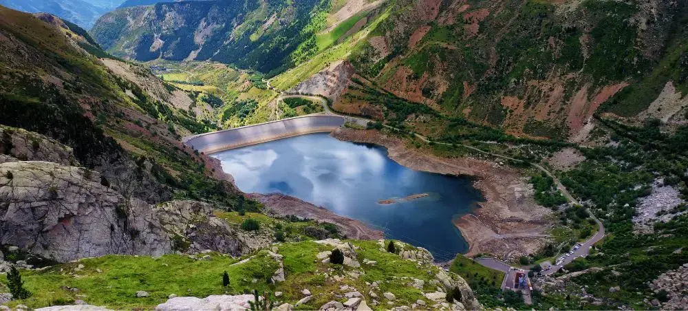 Mountain reservoir nestled in dramatic Spanish valley with winding roads and rugged terrain below