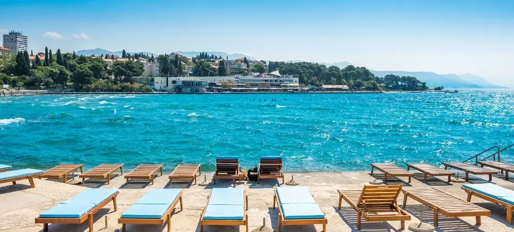 Luxury beachfront loungers overlooking turquoise Adriatic waters and Split's historic coastline in Croatia