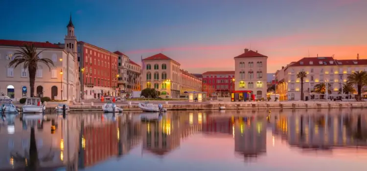Split's historic waterfront at sunset with colorful Mediterranean buildings reflected in calm harbor waters