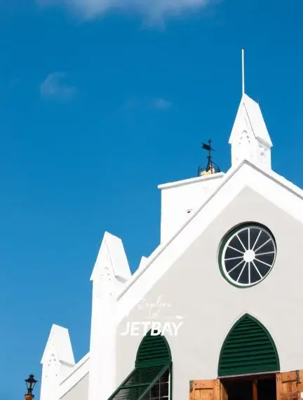 Historic white church with distinctive spire and green shutters in St Georges, Bermuda under bright blue sky