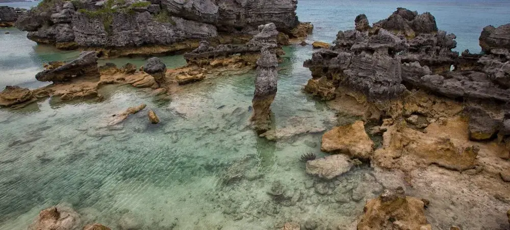Crystal clear turquoise waters and weathered limestone formations at St Georges Bermuda coastline