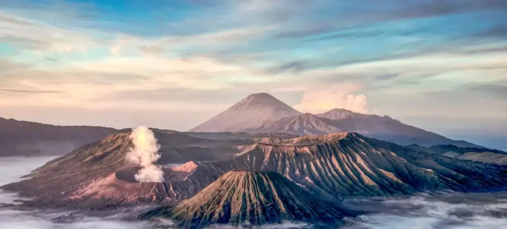 Mount Bromo volcanic crater with steam rising at sunrise, showcasing Indonesia's dramatic landscape near Surabaya