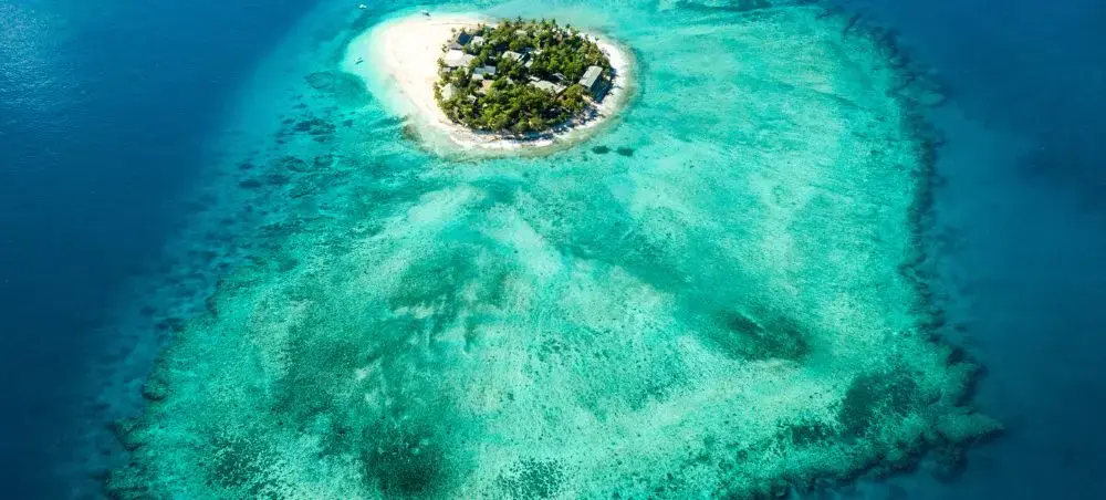 Aerial view of pristine private island surrounded by turquoise lagoon waters in Fiji's tropical paradise