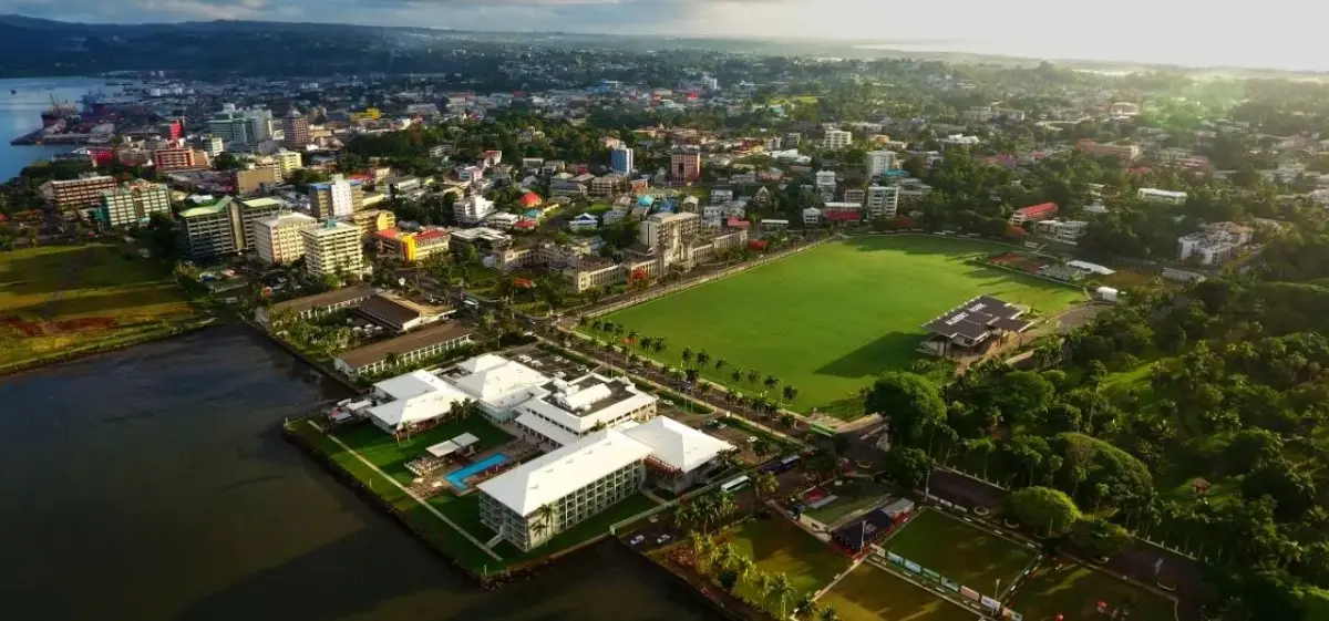 Aerial view of Suva's waterfront district showcasing modern buildings, green spaces, and harbor access for luxury travel