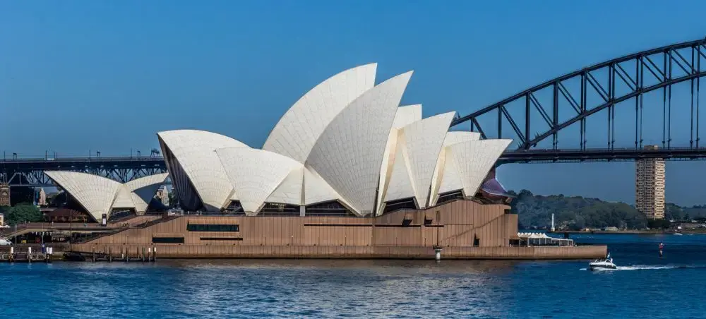Sydney Opera House iconic white shell architecture with Harbour Bridge spanning blue waters on clear day