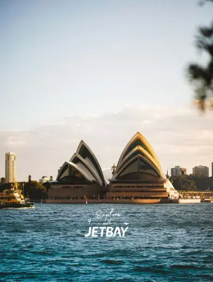 Sydney Opera House iconic shell architecture illuminated at golden hour with harbor waters and city skyline