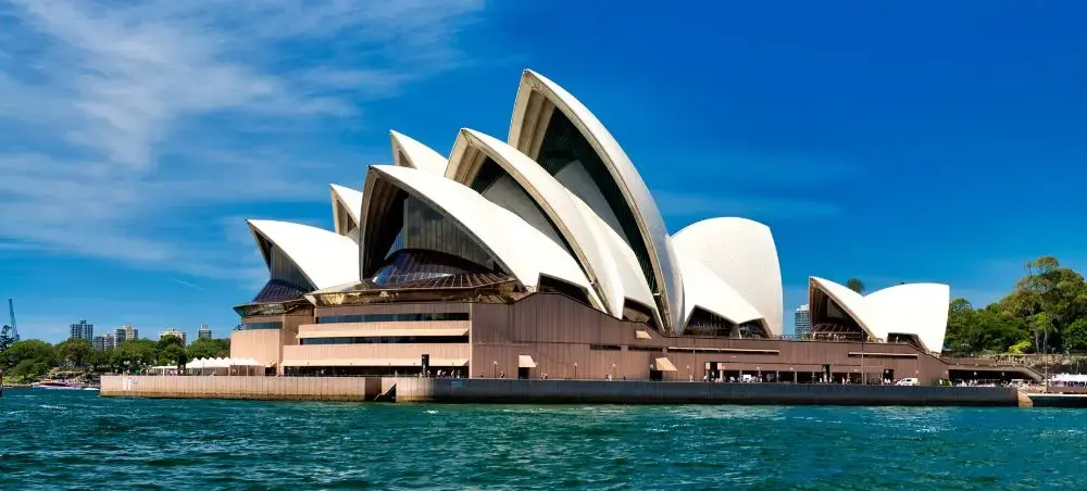 Sydney Opera House iconic white shell architecture viewed from harbor waters under brilliant blue sky