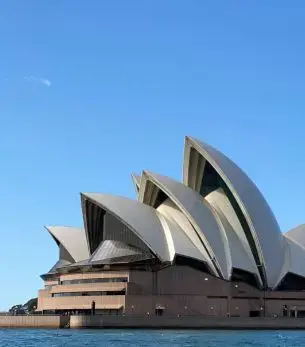 Sydney Opera House iconic white shell architecture against blue sky for luxury private jet travel