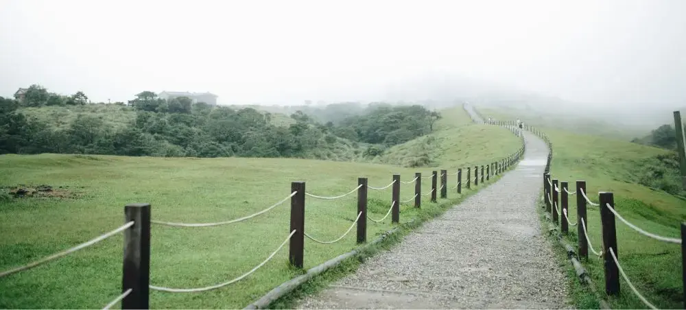 Misty hiking trail with wooden fence winding through green hills near Taipei, Taiwan countryside