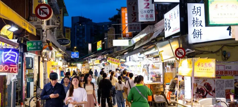 Bustling Taiwan night market with colorful neon signs, street food vendors, and crowds exploring local cuisine
