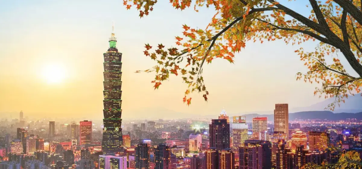 Taipei skyline at sunset featuring iconic Taipei 101 tower with autumn foliage framing the cityscape