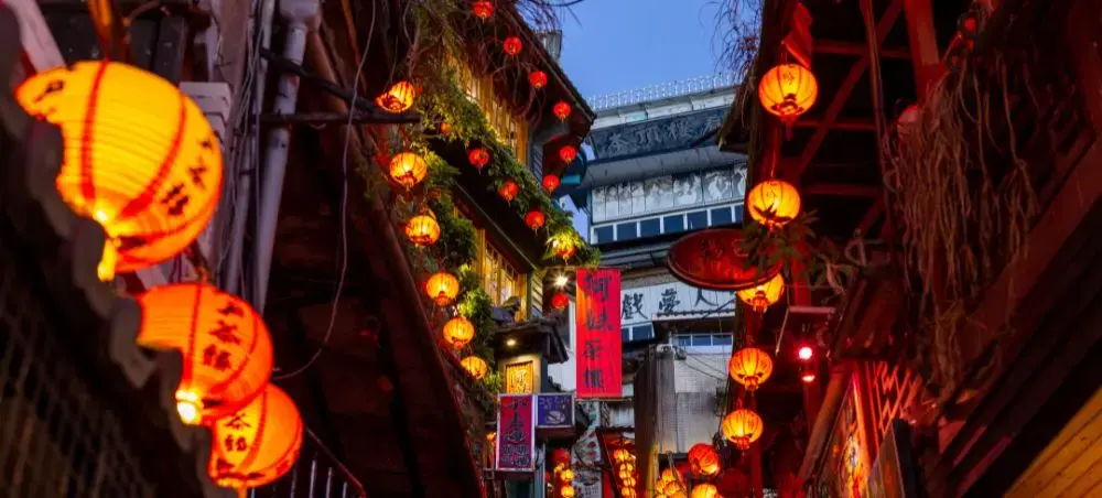 Traditional Taiwanese alleyway illuminated by red lanterns creating atmospheric evening ambiance in historic district